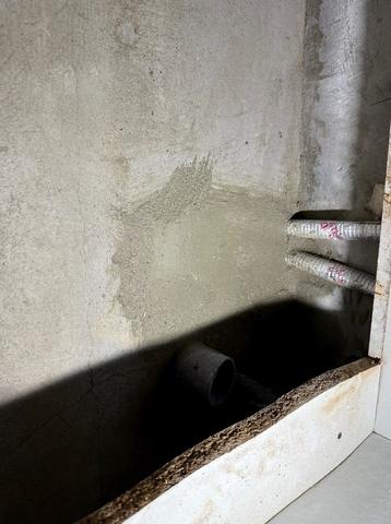누수탐지 작업 사진: 하부장 안쪽 콘크리트 벽에 배관 두 줄이 나와 있는 모습