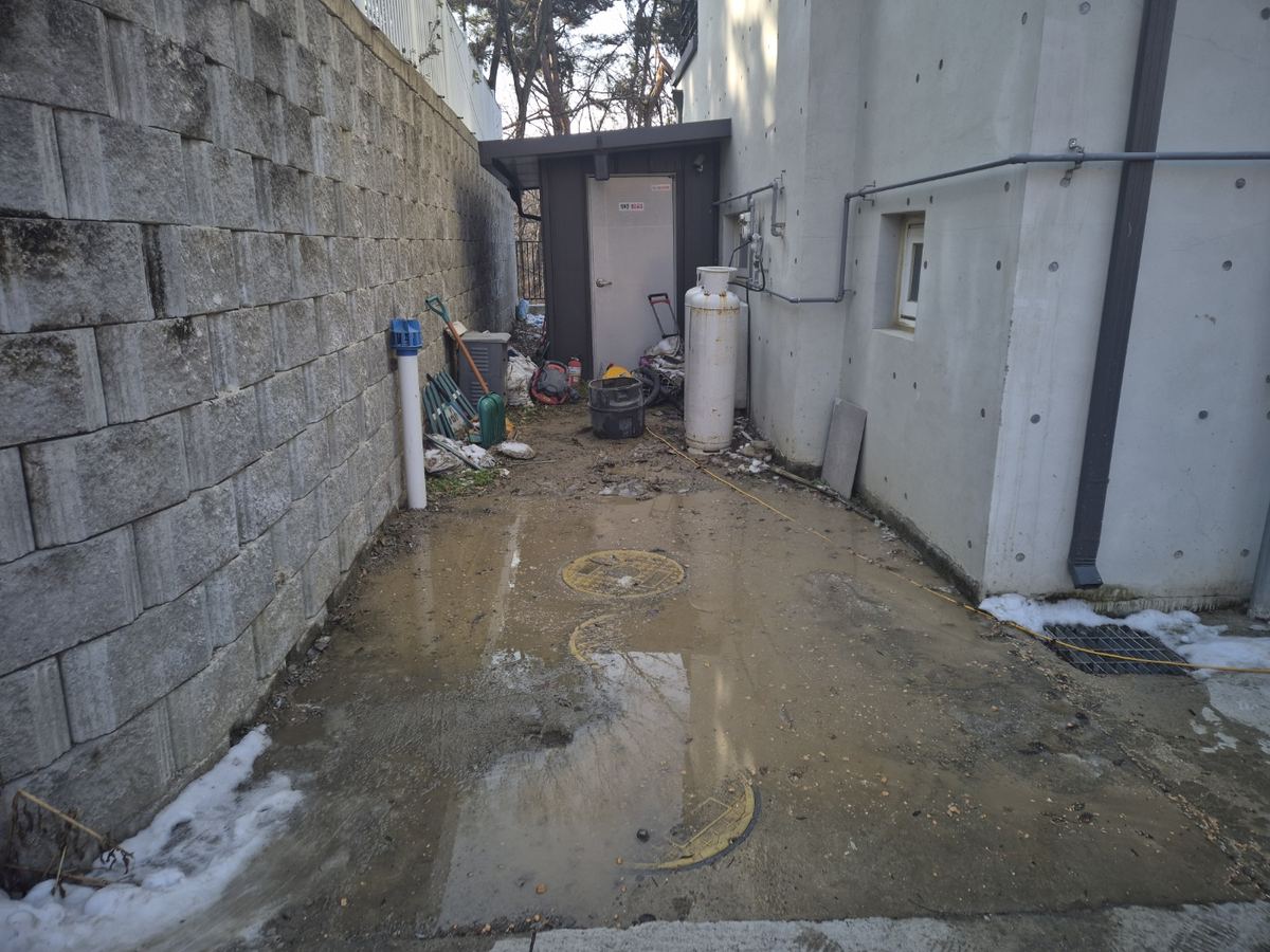 누수탐지 작업 사진: 단독주택 옆 통로 바닥에 물이 고인 모습